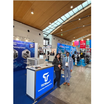 TECOI exhibition booth at an industrial trade show, featuring two professionals standing in front of a blue display counter and engineering equipment.