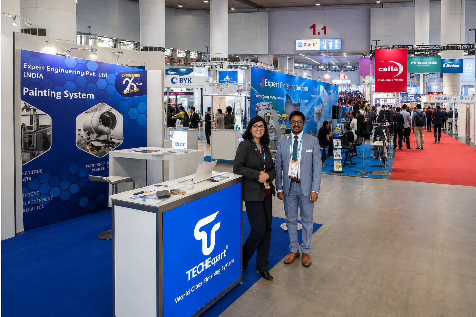 TECOI exhibition booth at an industrial trade show, featuring two professionals standing in front of a blue display counter and engineering equipment.